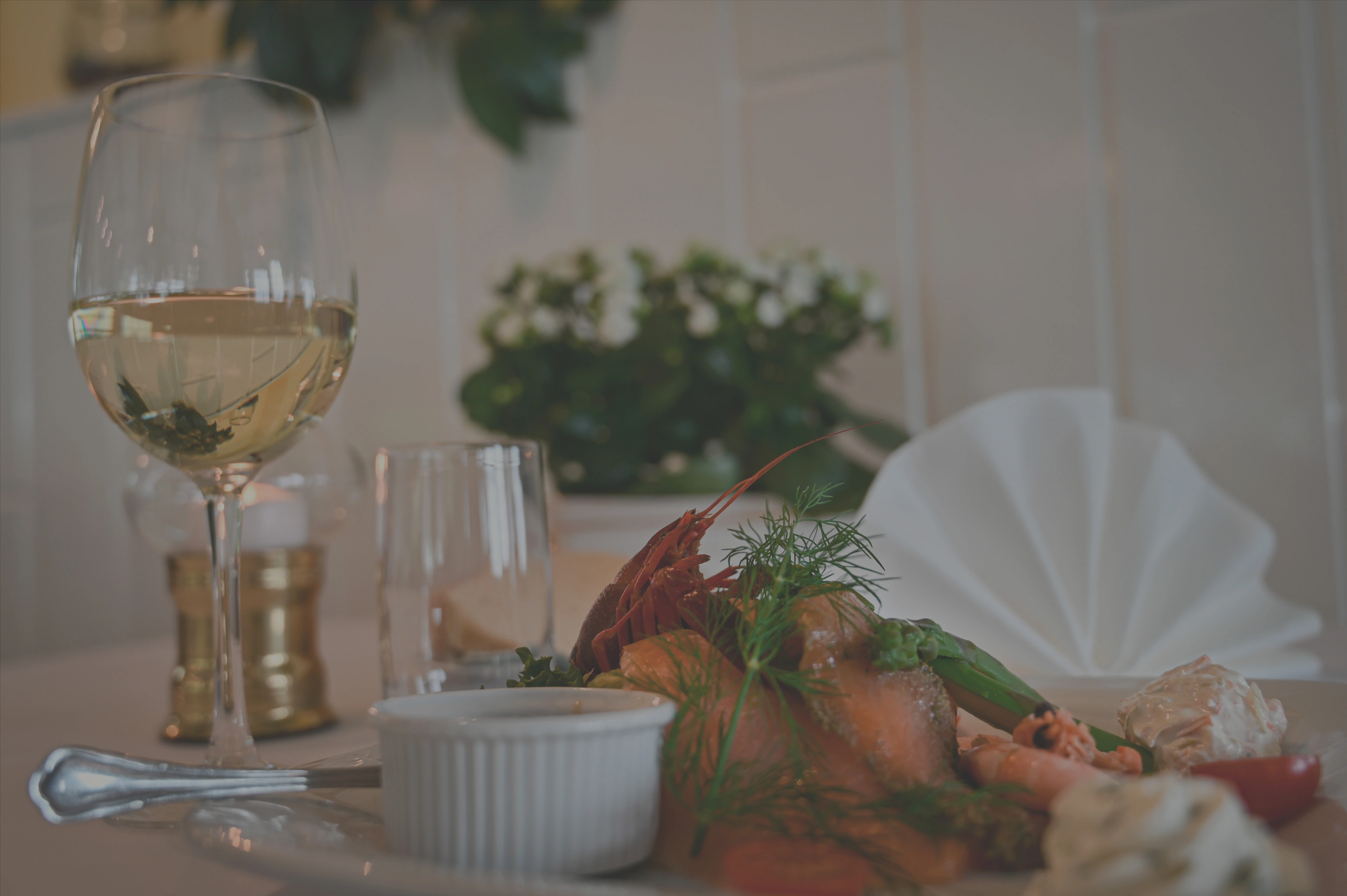 Billede af et glas hvidvin samt en ret bestående af jomfruhummer og laks